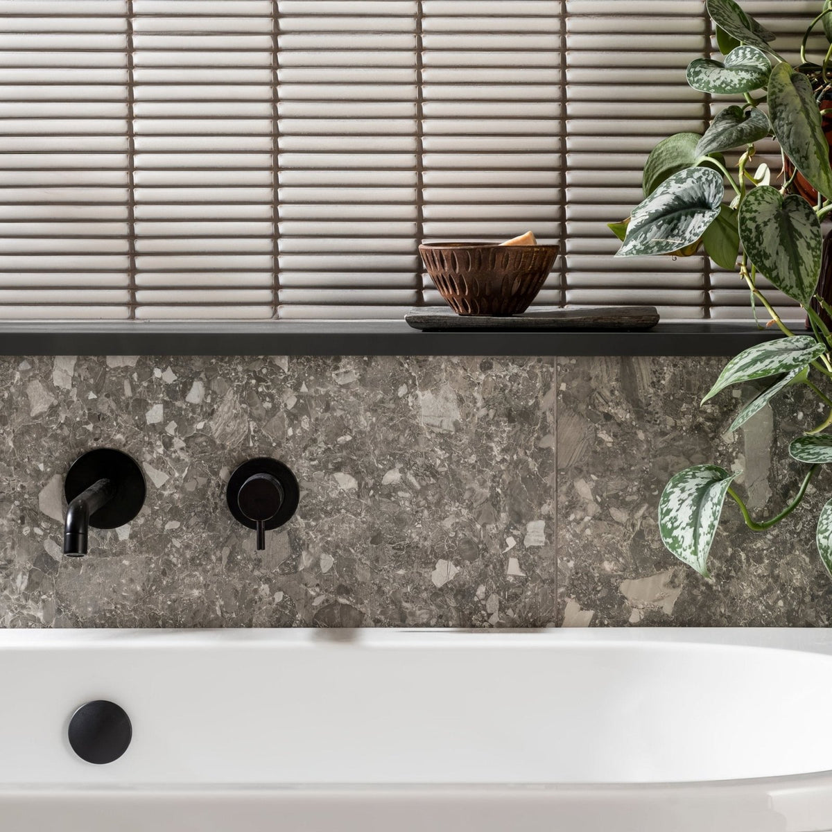Matchstick Ice white glass mosaic with a black wall-mounted bath tap