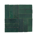 Dark green rectangular ceramic tiles arranged in a herringbone pattern from medina moss green zellige rectangle collection