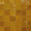 Warm amber ochre square handmade Moroccan zellige tile with polished slightly textured surface in a grid pattern