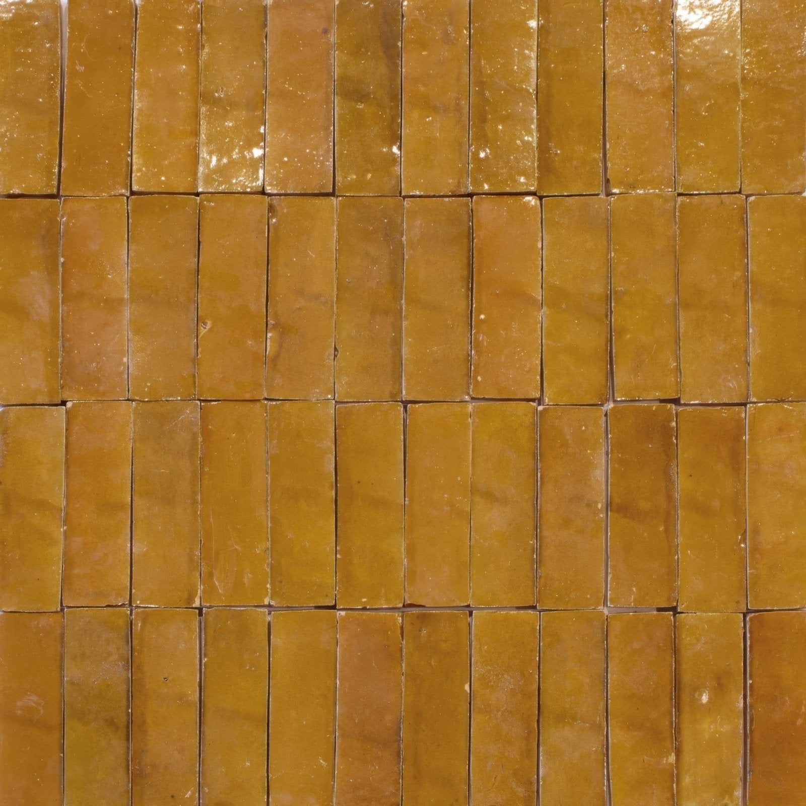 Medina ochre zellige rectangle warm amber-colored glossy ceramic tiles with uneven surface arranged in neat rows