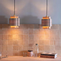 Two warm-toned rectangular pendant lights with wooden and metal accents hang above a tiled medina raw square handmade moroccan zellige tile countertop