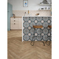 The metro bone ceramic gloss kitchen island features a patterned tile backsplash with teal white and dark gray geometric designs