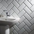 Metro white ceramic gloss sink with a sleek chrome faucet against gray herringbone subway tile backsplash
