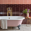 Mezzo Fantasia pink clawfoot bathtub with white porcelain interior and gold toned fixtures for elegant bathing