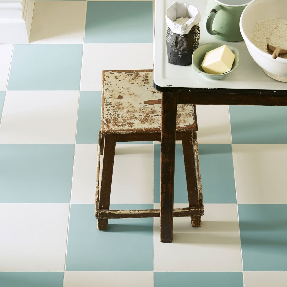 Weathered wooden stool with chipped paint showcasing rustic charm on milan cerva white porcelain tile floor