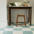 Dark wooden table with black enamel chipped top and rustic legs with matching stool under milan cerva white porcelain tile