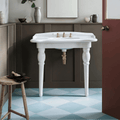 White ceramic pedestal sink with ornate gold-toned faucets and matching pipe complements milan gorani blue porcelain tile