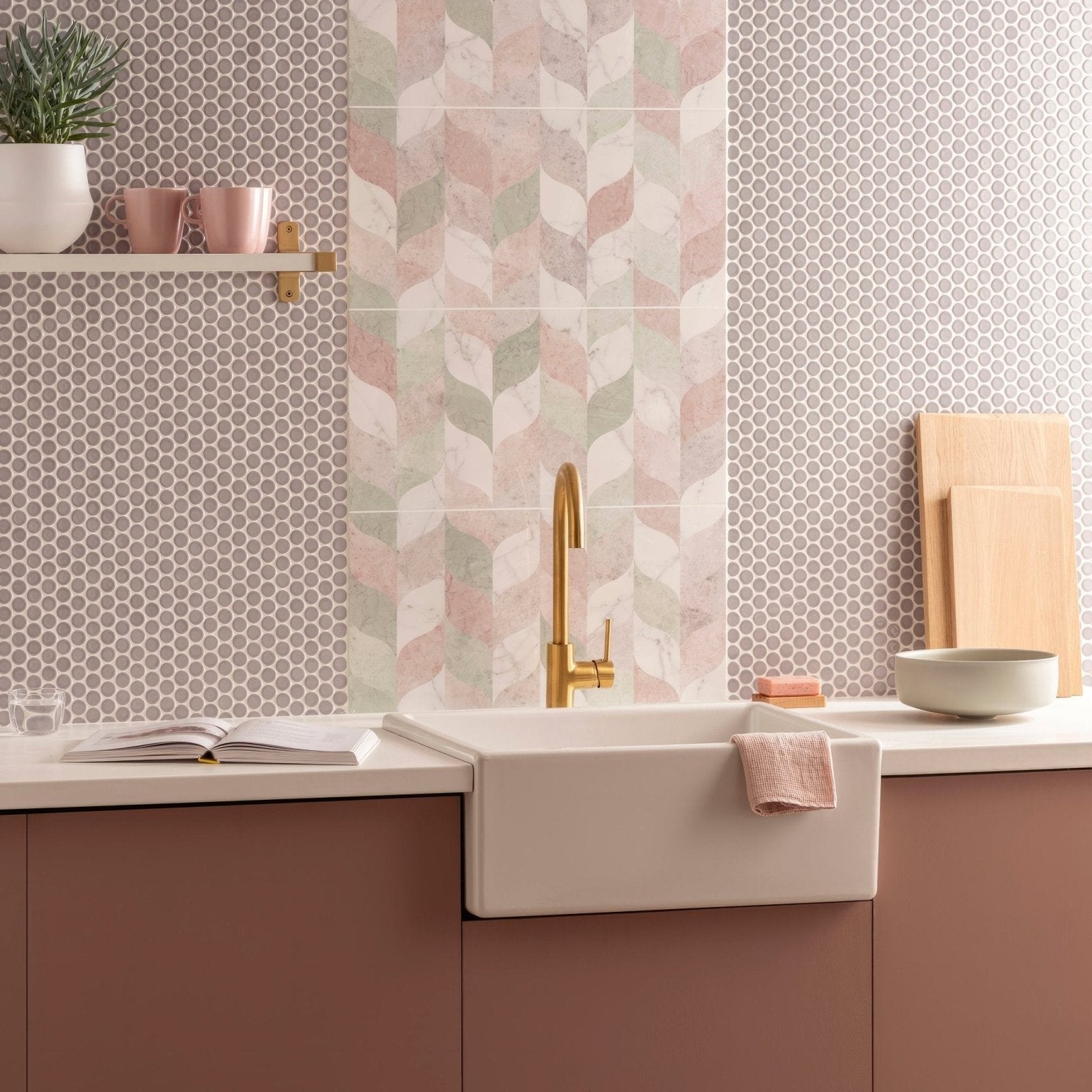 White farmhouse sink with gold faucet and pink towel beside mini grey penny round tile background