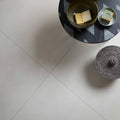 A round black and white geometric patterned side table with a matte finish paired with moderna grey porcelain tile