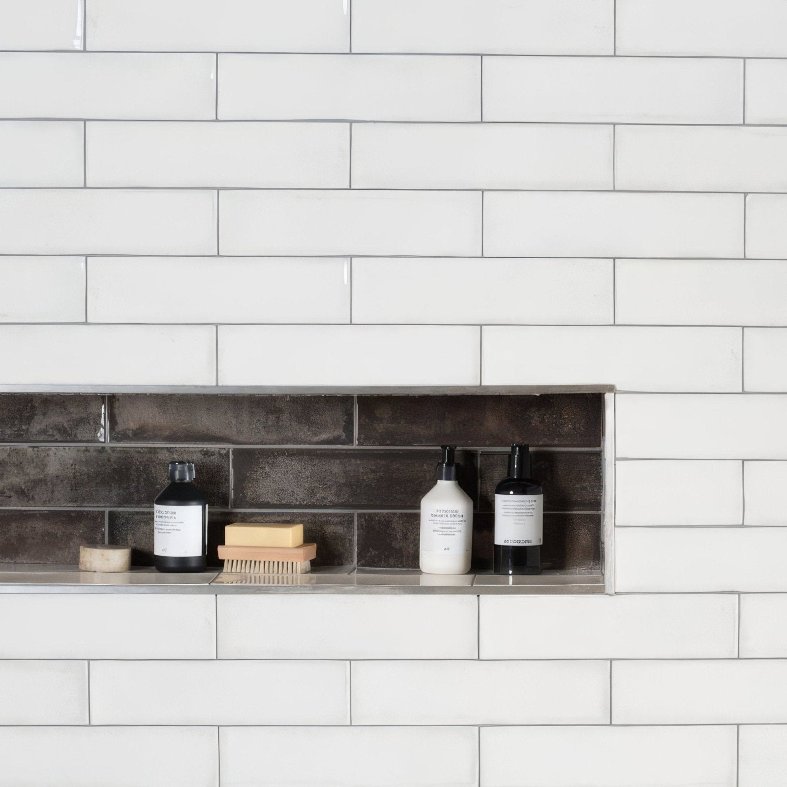 White rectangular tile wall with recessed shelf holding three bottles and a brush in montblanc anthracite 30x7.5cm