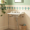 White ceramic pedestal sink with polished chrome legs and faucet featuring montmartre tube-lined single tile design