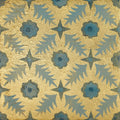 A decorative tile from neisha crosland atlas pine featuring a blue flower and star pattern on a gold textured background