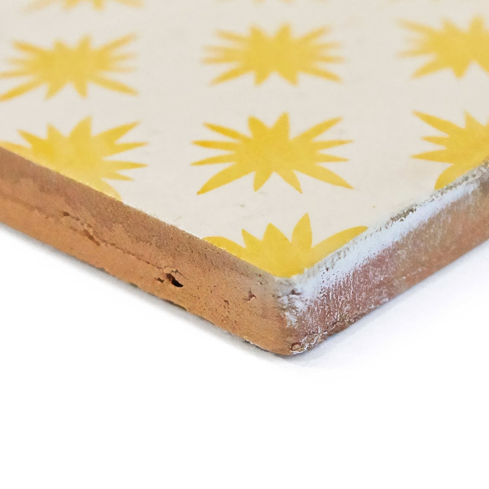 A square ceramic tile from neisha crosland atlas star anise buttercup with cream surface yellow starburst pattern and terracotta edge