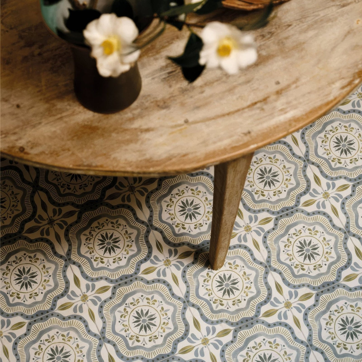 Patterned Nina Campbell Cochin Blue porcelain floor tiles with intricate floral and geometric designs in muted gray olive green and cream tones