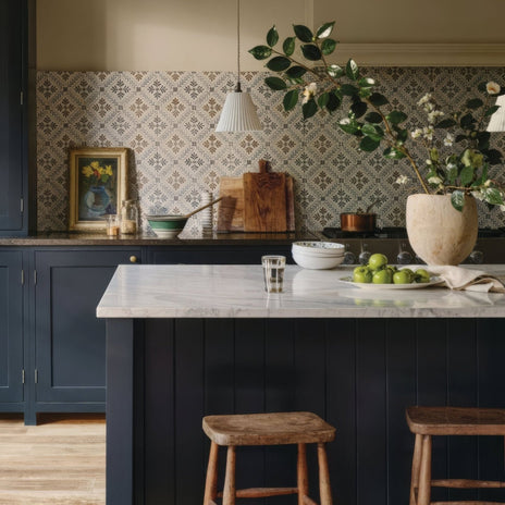 A beige ceramic vase with greenery and white flowers on a marble countertop featuring nina campbell goa indigo chocolate porcelain tile
