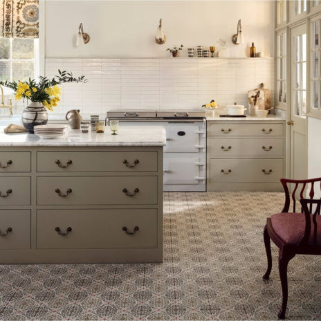 White vintage-style aga range cooker with brass handles and knobs featured in nina campbell la moulade chocolate porcelain tile setting