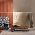 A stack of Nina Campbell Rivage Ivory glazed ceramic wall tiles in earthy terracotta, cream, and blue geometric patterns
