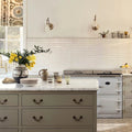 A ceramic vase with a black and white striped pattern holding yellow flowers paired with nina campbell rivage ivory glazed wall tile