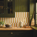 A white ceramic bottle with handle and matching cap on wooden countertop with nina campbell rivage ochre glazed wall tile