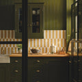 Dark green wooden kitchen cabinets with brass handles and glass-front doors styled with nina campbell rivage ochre glazed wall tile