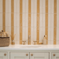The nina campbell rivage ochre glazed wall tile complements a white countertop with a gold faucet and oval sink basin