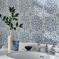 White ceramic vase with slender neck and rounded body holding green leafy plant featured on nina campbell seville blue porcelain tile