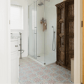 Glass shower enclosure with chrome fixtures and silver rainhead on nina campbell seville coral aqua porcelain tile wall