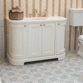 White bathroom vanity with curved edges gold-toned hardware and smooth countertop featuring Nina Campbell Seville Coral Aqua porcelain tile