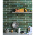 A round metallic colander with textured surface and handles in oasis ceramic green gloss finish