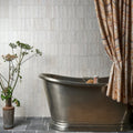 A sleek metallic freestanding bathtub oasis veloute ceramic white matt with brushed finish and elegant curves