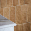 Tan rectangular oasis veloute ceramic cotto matt tiles with a textured stone-like finish on the wall