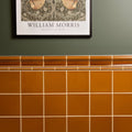 Warm amber-colored ochre field ceramic tiles with a glossy finish arranged in a grid with white grout lines