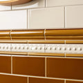 Ceramic tile border ochre omega moulding with glossy amber finish and white decorative bead accents