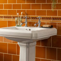 White ceramic pedestal sink with chrome faucets featured in ochre sigma moulding bathroom design