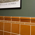 Warm amber ochre victoria moulding ceramic tiles with a glossy finish in a classic grid pattern and white grout lines
