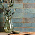 Oken Brick Green translucent green glass vase with flared neck and geometric facets holding olive branches
