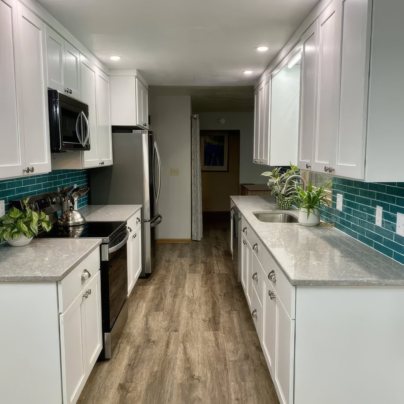 White shaker-style kitchen cabinets with silver hardware and teal onda aquamarine subway tile backsplash