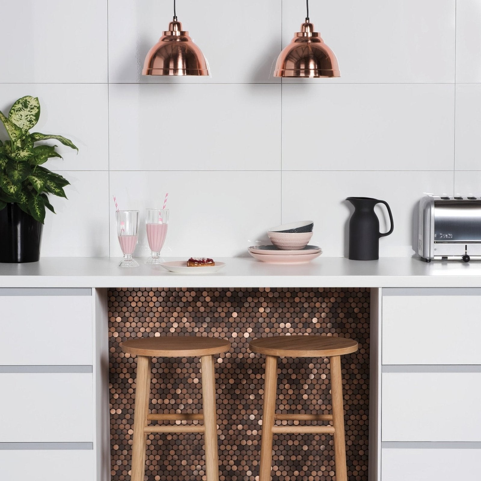Copper dome pendant lights with brushed metal mosaic finish hanging above white kitchen counter