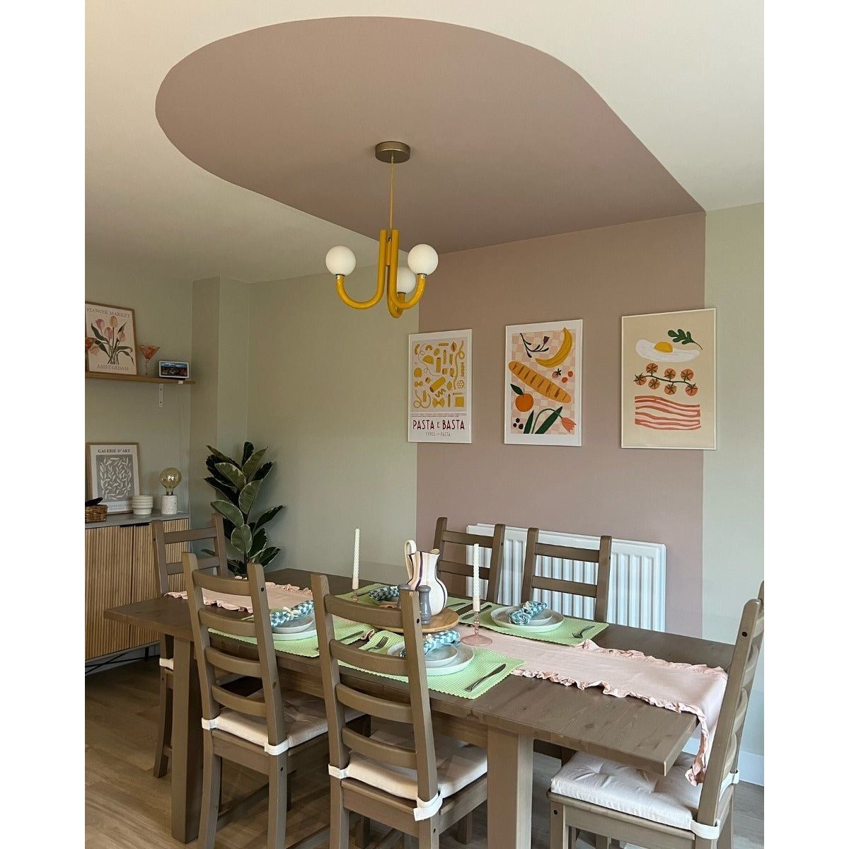 Wooden dining table with light brown finish and matching chairs set for a meal with green placemats and pink runner orchard pink