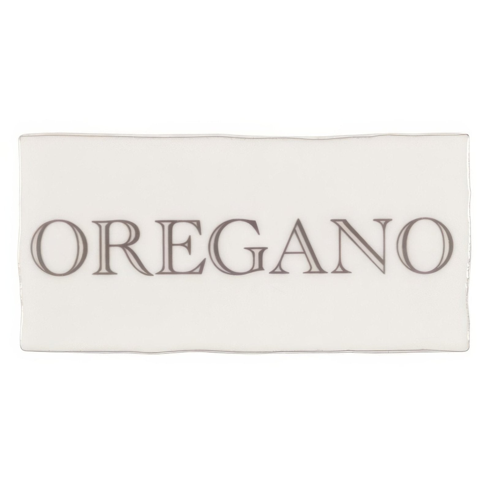 A rectangular white ceramic oregano dish with dark gray serif font on a grey cotton background