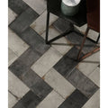 Osterley porcelain black brick tiles in dark gray and light stone arranged in a herringbone pattern for flooring