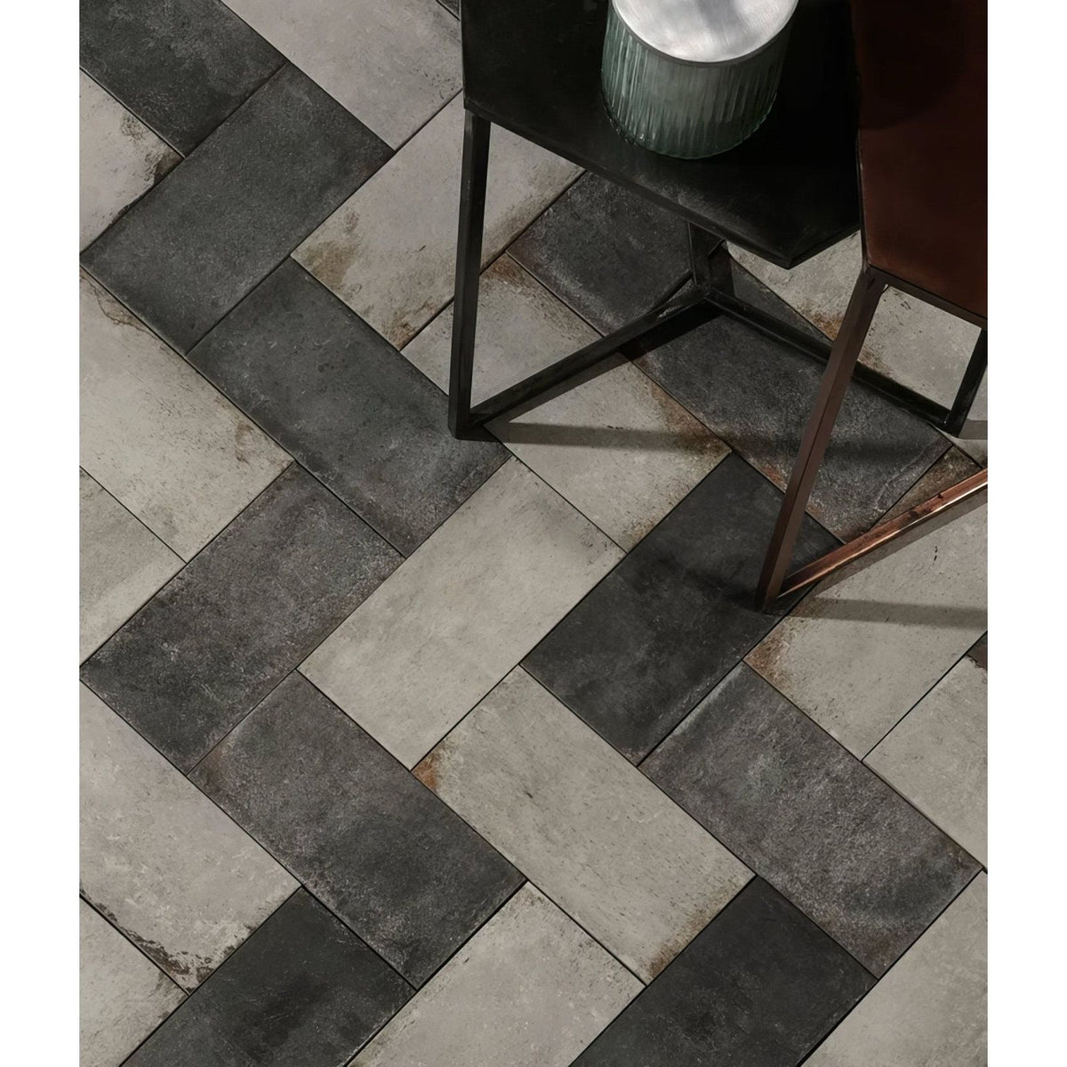Osterley porcelain black brick tiles in dark gray and light stone arranged in a herringbone pattern for flooring