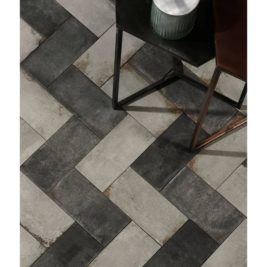 Osterley porcelain black brick tiles in dark gray and light stone arranged in a herringbone pattern for flooring