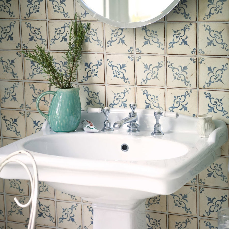 A turquoise ceramic pitcher with handle holding fresh green rosemary on paris isabelle patterned terracotta tile