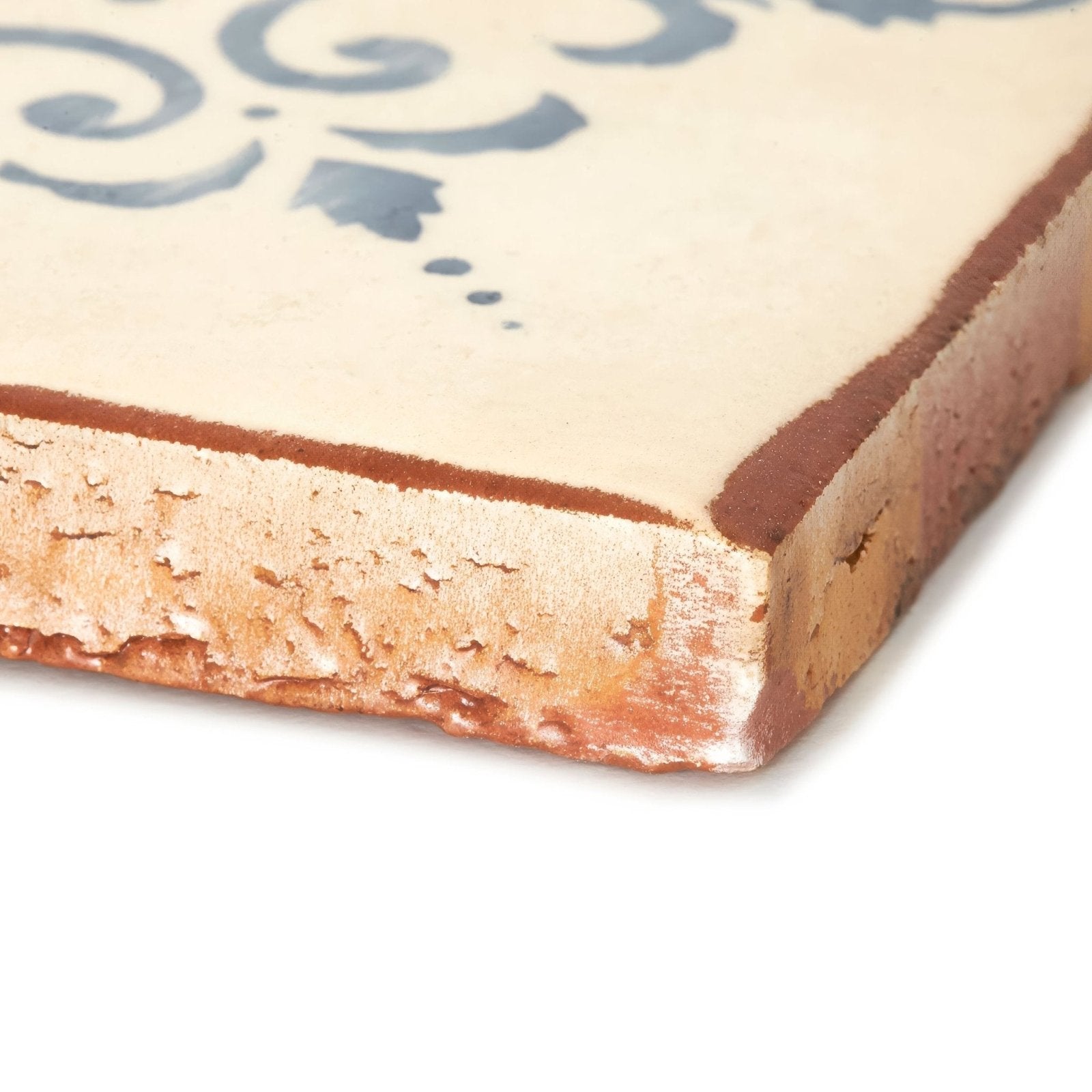 Cream-colored ceramic paris isabelle patterned terracotta tile with blue decorative swirls and rustic textured edge