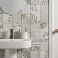 A white ceramic sink with a sleek black faucet against gray and beige patchwork botanical iris 60x30cm tiles
