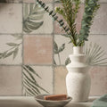 A white speckled ceramic vase with tiered organic shape holding green eucalyptus branches for patchwork botanical rose 60x30cm
