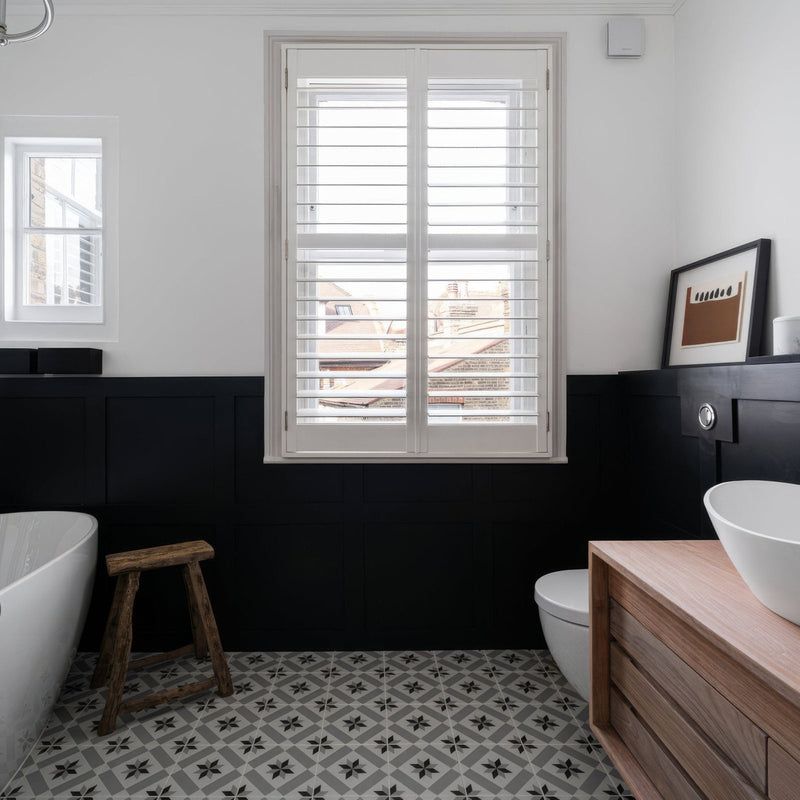 Bathroom with black wall, white bathtub, wooden stool, and Patisserie Sucre 1 Patterned Tiled floor.