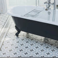 Black and white clawfoot bathtub with chrome fixtures against patisserie sucre 1 patterned tile wall