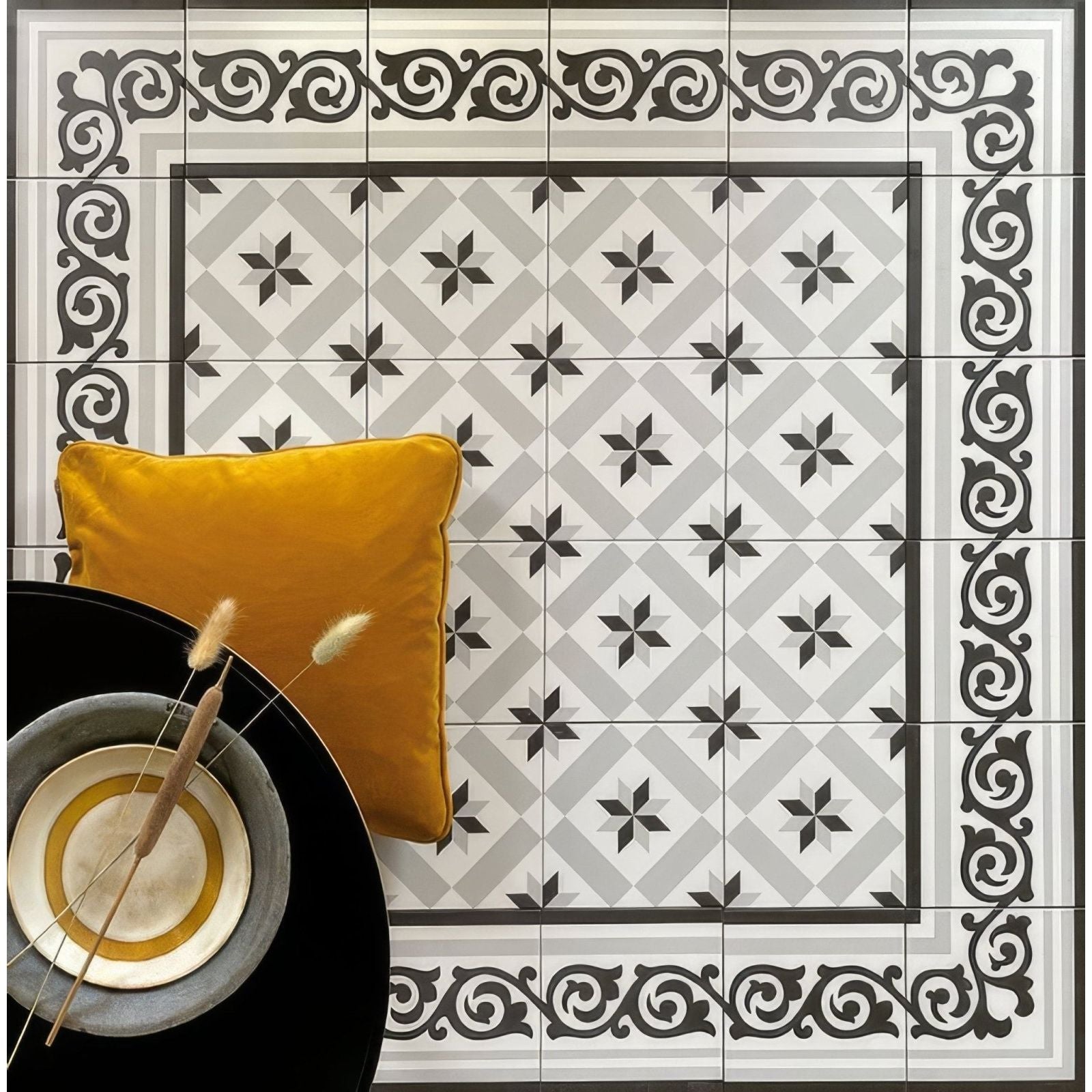 Patisserie Decorative tiles with geometric and floral patterns, a yellow pillow, and a black bowl with a decorative item on a tiled floor.